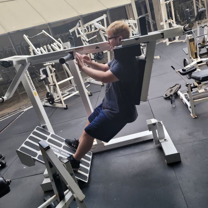 coach bryan teaching strength exercises to teen in gym